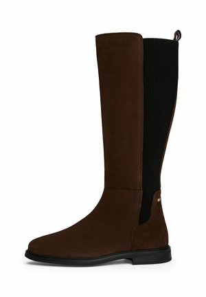 Stivale marrone in suede al ginocchio con pannelli laterali neri a costine, una superficie liscia, una suola robusta e un piccolo dettaglio logo vicino alla caviglia.