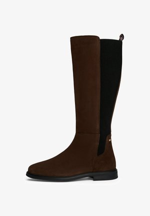 Botte en suède marron, haut jusqu'au genou, avec des panneaux latéraux en tissu côtelé noir, une surface lisse, une semelle robuste et un petit logo près de la cheville.