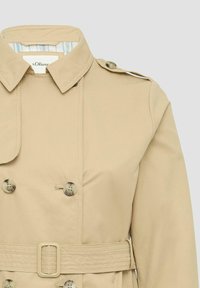 Beige Trenchcoat mit doppelter Knopfleiste, großen Knöpfen, Schulterklappen und einem taillierten Bund. Das Innenfutter zeigt ein gestreiftes Muster.