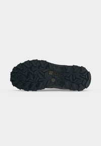 Μαύρη λαστιχένια σόλα παπουτσιού Jack Wolfskin με βαθιά, πολυκατευθυντικά πέλματα για πρόσφυση σε τραχύ έδαφος.