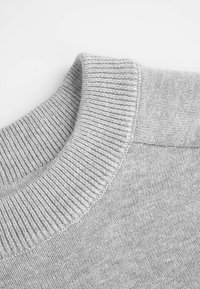 Jasnoszary sweter z teksturowanym, prążkowanym kołnierzem i gładkim korpusem. Tkanina wygląda na miękką z równomiernym wzorem dzianiny.