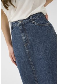 Denim krilo v temno modri barvi z oprijetim pasom, sprednjimi žepi in kontrastnim šivanjem. Tkanina ima rahlo teksturirano površino.