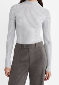 Jasnoszary prążkowany golf z długimi rękawami, o dopasowanym kroju i gładkiej fakturze. Do tego ciemnobrązowe, dopasowane spodnie.