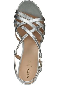 Sølv strappy høyhælte sandaler med kryssede metalliske stropper, spenne lukking, og en beige såle med merkevare. Glatt tekstur.