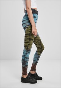 Färgglada tie-dye leggings i blå, grön och brun nyans, tillverkade av elastiskt material, med hög midja och smickrande silhuett.