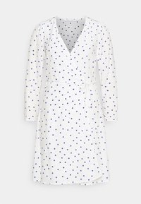 Robe blanche portefeuille à manches longues, ornée d'un motif à pois bleu marine. Conçue avec une taille à nouer et un décolleté en V.