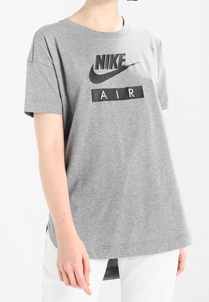 Camiseta de algodón gris con mangas cortas, con un logo negro de Nike y un gráfico "AIR" en un diseño discreto. Dobladillo redondeado en la parte posterior.