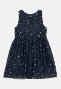 Ermeløs marineblå kjole med samlet midje, dekorert med et spredt hvitt stjernemønster og en liten knappelukking bak i nakken.