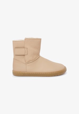 Stivaletto alla caviglia in pelle beige con cinturino in Velcro, punta tonda e fodera morbida. Presenta una suola testurizzata e un design minimalista.