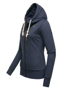 Granatowa bluza z zamkiem błyskawicznym i wysokim kołnierzem, z kremowymi sznurkami, brązowymi akcentami w postaci kołków oraz bocznymi kieszeniami. Wykonana z miękkiego, teksturowanego materiału.