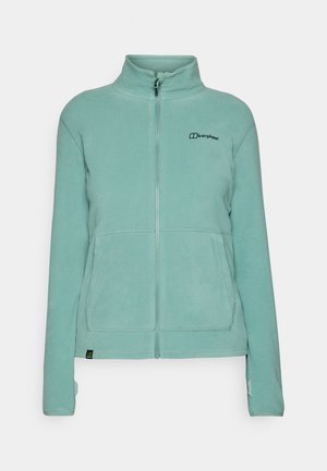 Veste en polaire de couleur bleu clair avec un col haut, une fermeture éclair intégrale, deux poches avant et un logo brodé sur la poitrine à gauche. Texture douce.