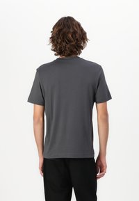 Camiseta de algodón gris con cuello redondo, mangas cortas y corte relajado. Textura suave, diseño liso, sin logotipos ni patrones visibles.