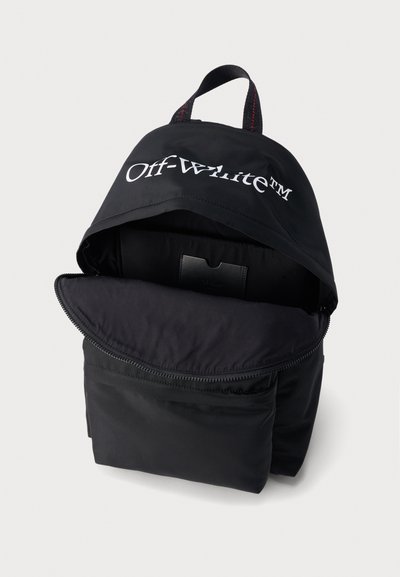 Sac à dos noir Off-White™ avec compartiment principal à fermeture éclair ouverte, poche interne visible, et poignée supérieure avec détail de surpiqûres rouges.