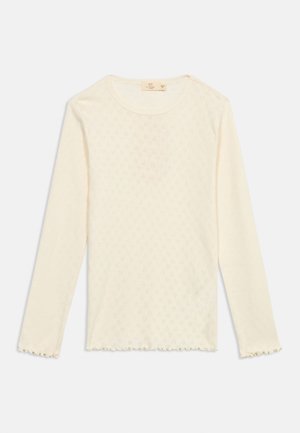 Cream-colored long-sleeve knit top with subtle diamond pattern, round neckline, and lettuce-edge hem on sleeves and bottom.