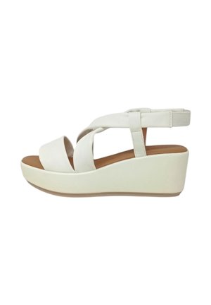 Sandali wedge bianchi con cinturini incrociati, una soletta imbottita e una finitura liscia e lucida. L'altezza del wedge scende gradualmente per offrire supporto.