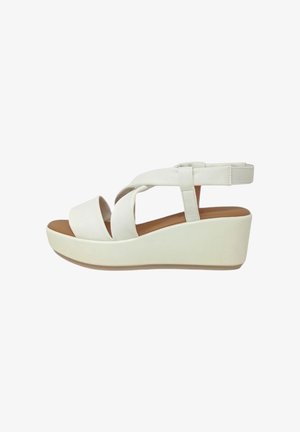 Sandali wedge bianchi con cinturini incrociati, una soletta imbottita e una finitura liscia e lucida. L'altezza del wedge scende gradualmente per offrire supporto.