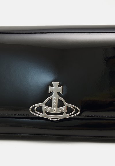 Portefeuille en cuir verni noir avec un emblème métallique argenté présentant une couronne et un design circulaire. Texture lisse et apparence élégante.