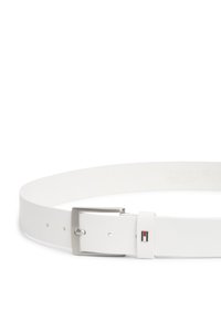 Άσπρη δερμάτινη ζώνη με λαμπερό ασημένιο μεταλλικό αγκράφα. Διαθέτει μικρό κόκκινο, λευκό και μπλε έμβλημα κοντά στον αγκράφα. Ομαλή υφή, ρυθμιζόμενο μέγεθος.