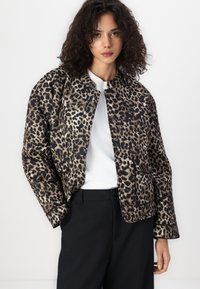Veste en imprimé léopard avec un col rond, en tissu texturé, dotée d'une fermeture à boutons et d'une poche plaquée, associée à un pantalon noir.