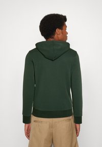 Felpa verde scuro con cappuccio regolabile, polsini e orlo a costine, realizzata in un tessuto morbido, con una vestibilità comoda e senza loghi visibili.