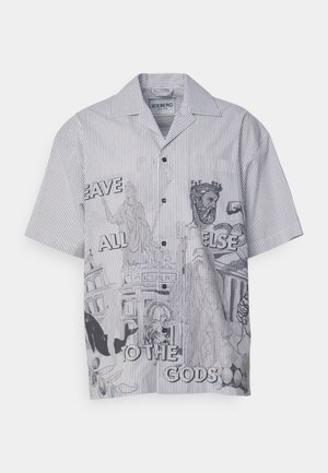 Short-sleeve button-up shirt in black and white stripes featuring graphic designs and text, with a camp collar and chest pocket detail.