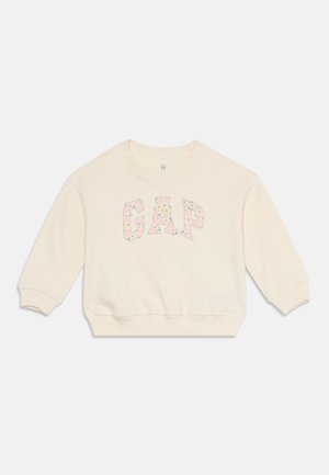 Kreemikas pikkade varrukatega dressipluus GAP logo ja pastelses toonis lillemustriga ees.