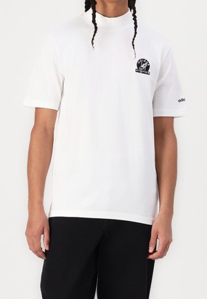 Biała bawełniana koszulka z wysokim dekoltem, krótkimi rękawami, z czarnym logo "adidas originals" na klatce piersiowej i rękawie.