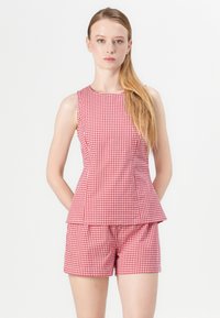 Rød og hvid gingham mønstret ærmeløs peplum top med matchende shorts, der har en tætsiddende silhuet og en glat tekstur.