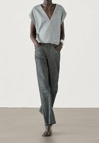 Gray, loose-fitting v-neck top with short sleeves, paired with vertical-striped, wide-legged pants in dark gray tones. Sandals included.