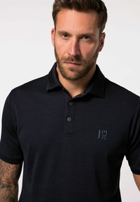 Polo shirt blu scuro con tessuto testurizzato, maniche corte e apertura con due bottoni. Presenta un piccolo logo sul lato sinistro del petto.