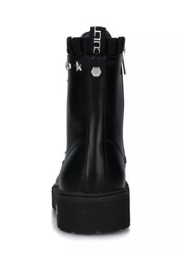 Stivale alla caviglia nero in pelle liscia con suola testurizzata, caratterizzato da una chiusura con zip, dettaglio con logo sul retro e decorazioni metalliche.