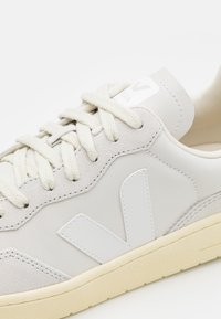 Λευκά δερμάτινα και σουέτ αθλητικά παπούτσια με κρεμ σόλα από καουτσούκ, καλοδιορισμένες ραφές και λευκή λογότυπη λεπτομέρεια στο πλάι. Διαθέτει μπεζ κορδόνια.