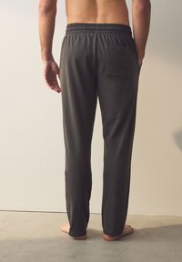 Mørkegrå bukser med afslappet pasform og elastisk taljebånd, med en enkelt baglomme, lavet af blødt, let stof.