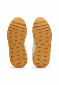 Las suelas de las zapatillas blancas presentan una parte inferior de goma naranja texturizada con estrías horizontales y verticales, y la grabación "TOMMY JEANS."