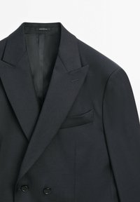 Blazer doppiopetto grigio scuro realizzato in tessuto testurizzato, con ampi rever, tasca sul petto e due bottoni neri sul davanti.