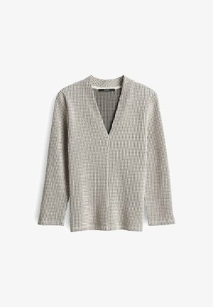 Beige gebreide cardigan met lange mouwen, klein geruit patroon, V-hals en geen knopen of zichtbare sluitingen.