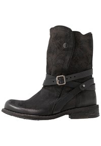 Bottes de cowboy noires avec un design texturé, comprenant une sangle décorative avec une boucle, fabriquées en cuir et une tige en tissu à motif.