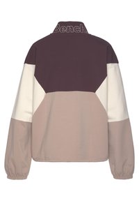 Veste-pull à blocs de couleurs avec un col montant, composée de panneaux violet profond, crème et beige doux. Fabriquée en tissu lisse avec des poignets élastiques.