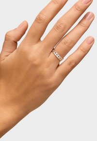 Anello d'argento con una fascia liscia caratterizzata da ritagli rettangolari distanziati in modo uniforme. Indossato su una mano con tono della pelle naturale.