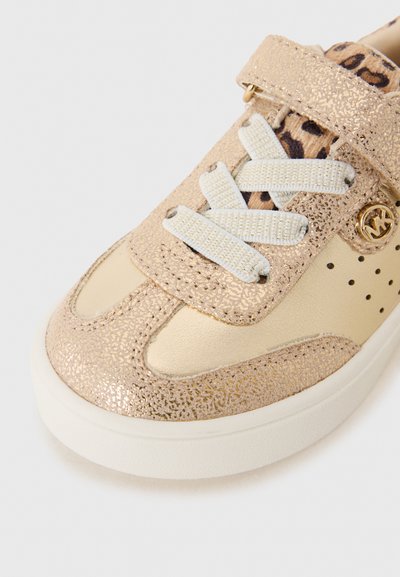 Zapatilla de tono dorado con un acabado brillante, cordones blancos, correa de velcro y forro de estampado de leopardo, con puntera redondeada y suela blanca.