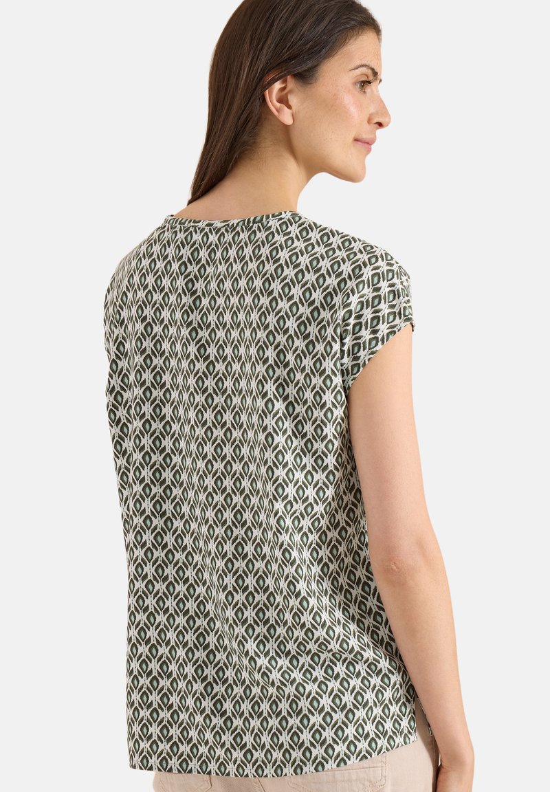 Femme en haut à manches courtes à motif géométrique vert et blanc, vue de dos et de côté sur fond uni.