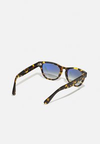 Óculos de sol em padrão tartaruga com formato em gatinho. Lentes azuis degradê e acabamento suave e brilhante. Braços ajustáveis para maior conforto.