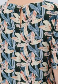 Blumenbluse mit grünem Hintergrund und mehrfarbigen Blattmustern. Schlüsselrückenverschluss mit einem kleinen Knopf. Kurze Ärmel.