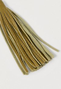 Skórzany chwost w kolorze brązowym z wieloma cienkimi paskami, ukazujący zarówno gładką, jak i zamszową teksturę na jasnym tle.