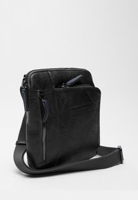 Borsa a tracolla nera in pelle con finitura testurizzata, due tasche con zip e spallaccio in tessuto. Forma rettangolare con accenti minimi.