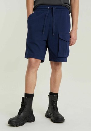 Pantaloni corti in cotone blu navy con vita elasticizzata e coulisse, dotati di tasche laterali e una grande tasca cargo sulla gamba sinistra.