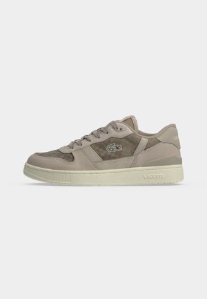Baskets Lacoste beige et taupe avec panneaux latéraux texturés, lacets gris, semelle en caoutchouc et logo Lacoste sur le côté et le talon.