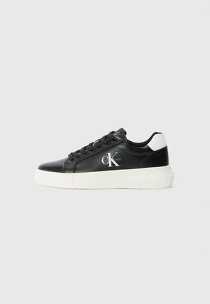 Svart läder låga sneakers med vit gummisula, rund tå, platta snörningar och prägling av logotyp på sidan. Kontrastfärg på hälen.