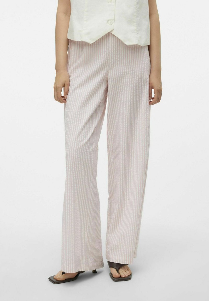 Roze en witte gestreepte wijde pantalon van een lichte, textuurstof. Heeft een ontspannen pasvorm en een lichte glans. Platte schoenen maken de look compleet.