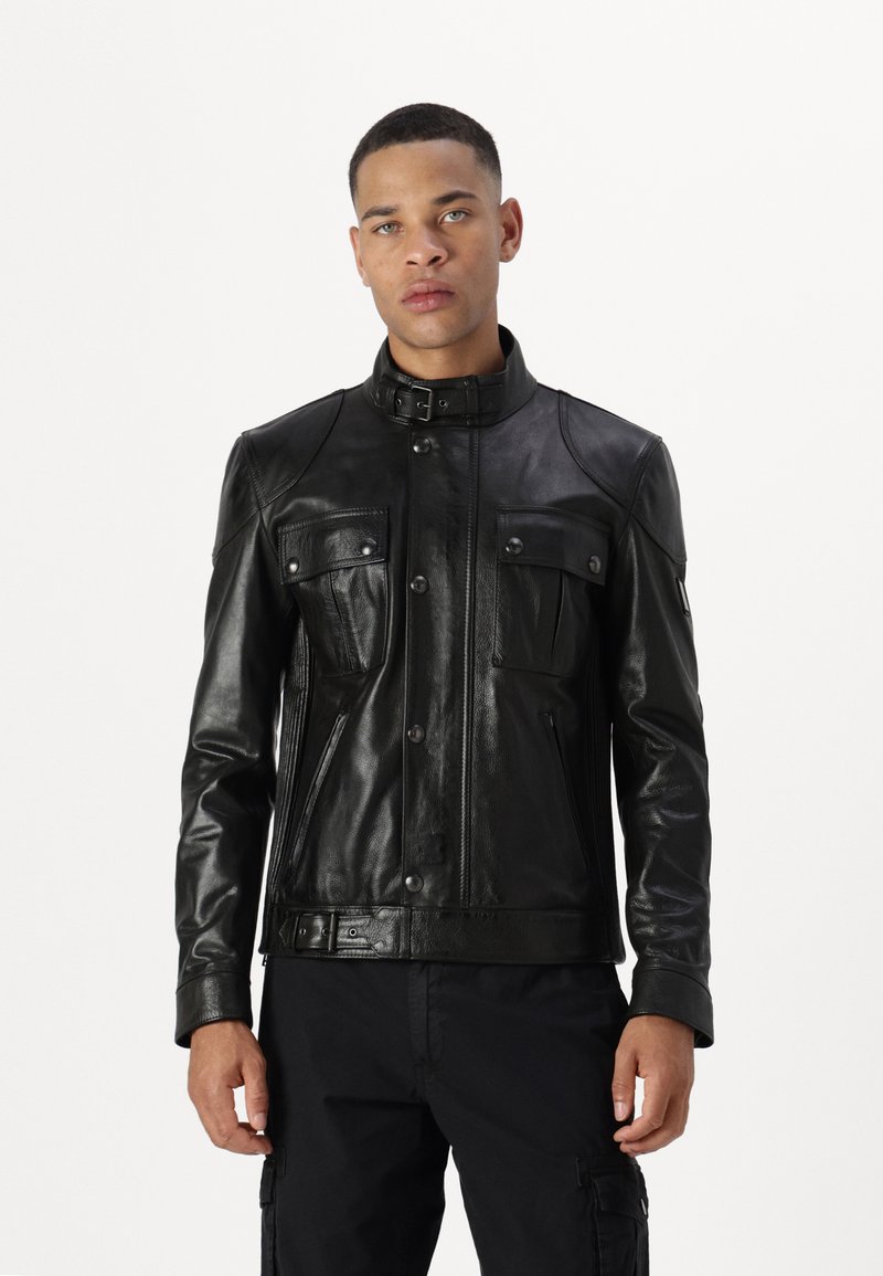 Veste en cuir noir avec un col haut, devant boutonné et deux poches poitrine. Présente une texture lisse et des accents matériels minimalistes.